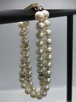 Pearls draped over a display bar showing two strands and round shape