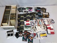 Long shot showing white storage box filled with sleeved cards plus loose piles of various insert and memorabilia cards