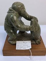 Front view of soapstone carving on wood base with identification tag visible