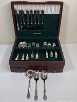 Full set of Oneida cutlery arranged in a wooden case with slots and velvet lining showing knives, forks, and spoons.