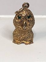 Front view of the Ookpik owl pendant showing textured body and emerald eyes