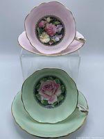 Both tea cup and saucer sets in pink and green displayed, showing front view.