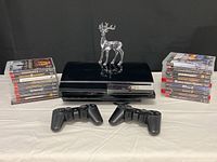 Wide shot of PS3 console with stacked game cases on either side and two controllers in front, decorative reindeer on top