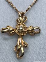Close-up of the rose gold cross pendant front showing floral center and diamond