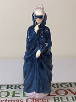 Front view of Royal Doulton Masque porcelain figurine showing woman in blue cloak and blue mask.