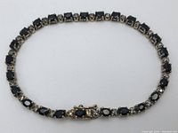 Full view of bracelet laid in a circle showing all sapphires, diamonds and clasp