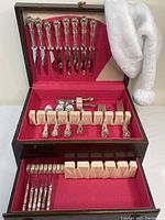 Wooden case opened showing top tier with eight silver-handled knives with stainless blades inserted in felt-lined slots