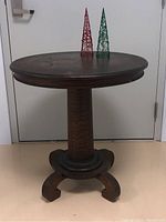 Full front view of round table with pedestal base and scrolled feet