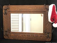 Front view of mirror showing oak frame and brass hooks