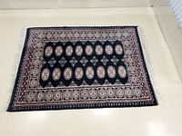 Full view of the blue Bokhara pattern rug showing overall design and border