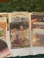 Collection of vinyl album covers laid out including Jackson Browne, Peter, Paul and Mary, Bloomsweet Steam and Asian pressed albums showing condition and variety.