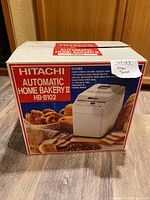 Front of the original product box showing the model, brand, and features of the Hitachi Automatic Home Bakery II Bread Maker HB-B102.