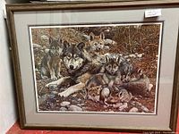 Full view of framed artwork showing wolf mother with pups in natural setting, detailed image with wood frame and matting