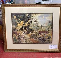 Framed print of garden scene featuring flowers and a wrought iron gate with visible sailboats in the background.