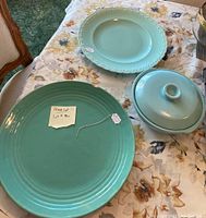 Overview of three aqua-colored California pottery pieces on floral tablecloth: Bauer 15 inch platter, Vernonware 14 inch braided rim platter, La Solana covered casserole