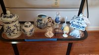 Overall display of all porcelain items on a dark glass table against a wall with an outlet.