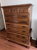 Full view of the wooden chest of drawers showing all drawers and the glass top.