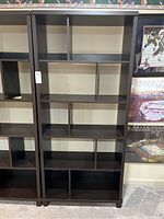 Front view of tall dark wood display shelf showing all compartments and layout