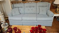 Front view of the blue and white gingham patterned sleeper sofa with tufted back cushions and two matching throw pillows.
