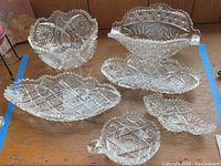 Top view of all six assorted cut glass and crystal bowls displayed on wooden surface