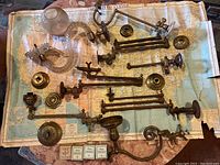 Disassembled antique gas light parts laid out on a vintage map, showing brass components, glass globes and valves.