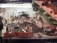 Wide view of the workbench and pegboard filled with vintage hand tools including saws, clamps, hammers, and baskets of small tools