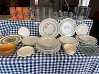 Wide view of assortment showing dishes, glassware, and bowls on blue and white checkered tablecloth.