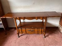 Full view of the mid century modern Bassett buffet table with drop leaves extended and visible lower shelf and drawer.