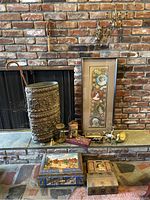 Wide view of lot including brass umbrella stand, framed art calendar, brass figurines on hearth, vintage metal boxes on floor, and wall-mounted candle sconces.