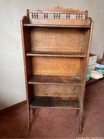 Full view of the wooden farmhouse jelly jar cabinet showing three shelves and decorative spindle back rail