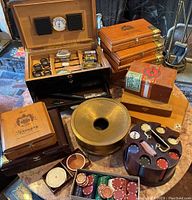 Various angles showing the collection of vintage humidor and tobacciana boxes, poker chips, spittoon and other smoking accessories grouped on a table.