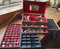 Three vintage jewelry boxes on table showing compartments filled with various jewelry pieces and watches.