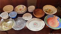 Full display of assorted vintage bowls, platters, and chargers varying in materials and size, showing condition and design details.