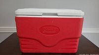 Front view of red Coleman cooler with white lid and embossed logo.