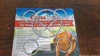 Metal Coors Light Beer Can Chicken Holder with multiple circular loops and a central ring, displayed on top of its branded packaging with Coors Light graphics and cooking instructions.