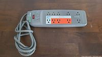 Full view of gray Smartwood Smart Surge power bar with power cord coiled beside it.