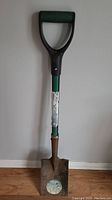 Full view of the Yardworks garden spade showing the black D-handle, green shaft, and metal blade with some wear and labels.