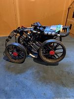Folded golf cart showing wheels and frame on blue carpet with wood and drywall background.