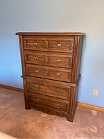 Front view of the highboy dresser showing all 5 drawers and brass knobs and handles.