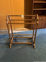 Front view of wooden quilt rack showing three horizontal bars and scalloped side supports.