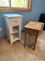 Photo showing white bathroom cabinet and wood table side by side near window.