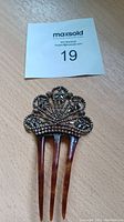 Full view of the antique hair comb showing decorative top and four prong faux tortoiseshell base.
