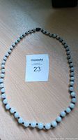 Full view of the white jade bead necklace laid out flat showing round beads and clasp.