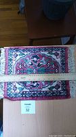 Top view of the miniature Persian rug with ruler placed across the width, showing size approx 28cm