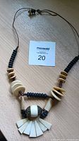 Photo of bone necklace showing its beads and carved bone elements on a leather string.