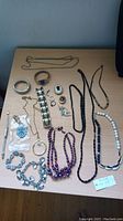 Full view of all jewelry pieces laid on table, showing necklaces, bracelets, rings, brooches in various metals and styles