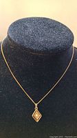 Sarah Cov gold-tone chain necklace with diamond-shaped pendant and single faux pearl on black display bust
