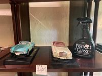 Photo shows two collectible Franklin Mint antique toy cars in blue and white, each on a black base, alongside a bottle of Perfect Glass cleaner.