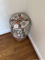 Full view of the ceramic garden stool showing circular flat top with intricate floral and medallion pattern around a square cutout in center.