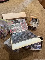 Binder open to show Star Wars cards in plastic 9-pocket pages, cardboard box of assorted cards on right, Ziploc bag of cards on left